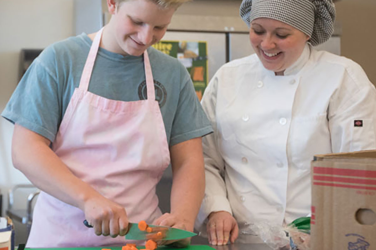 A teacher educator works with a student in a classroom setting. 