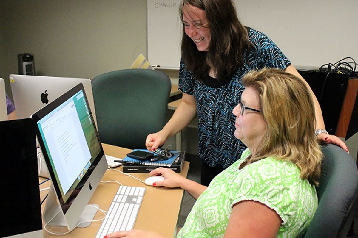 Two participants engaged in creating educational content on a computer.