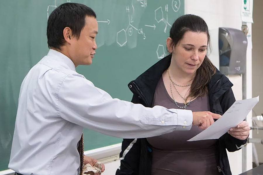 Two individuals reviewing educational materials in a classroom setting.