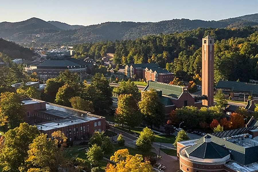 Aerial view of a university campus with academic buildings, trees, and a bell tower.