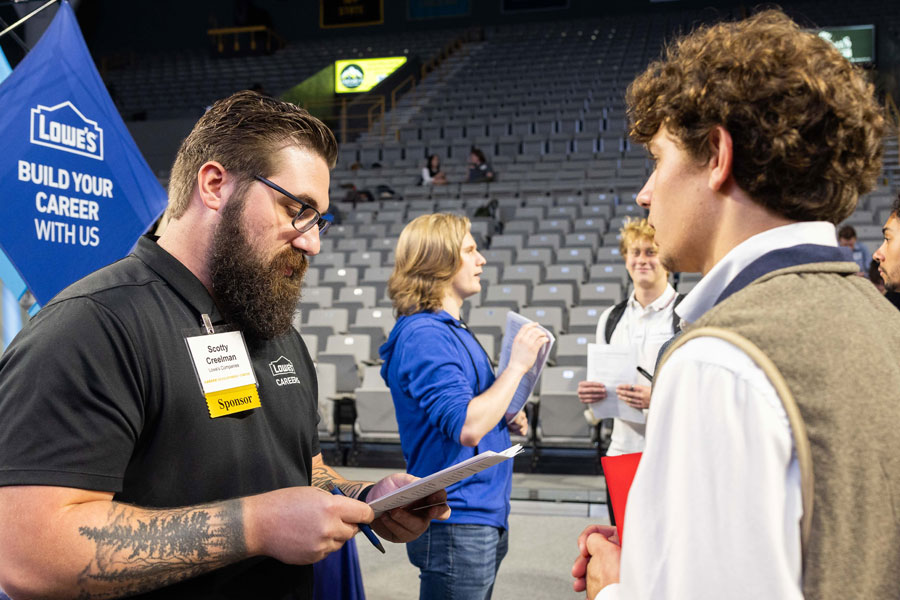 Employer representative reviewing documents with a student during a campus career event.