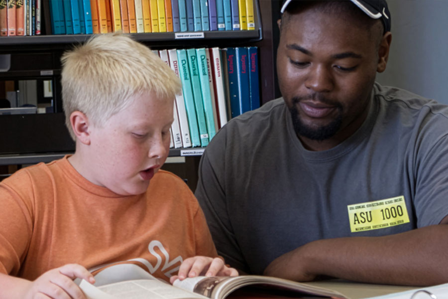 Two individuals engaged in a learning or tutoring session within a library environment.