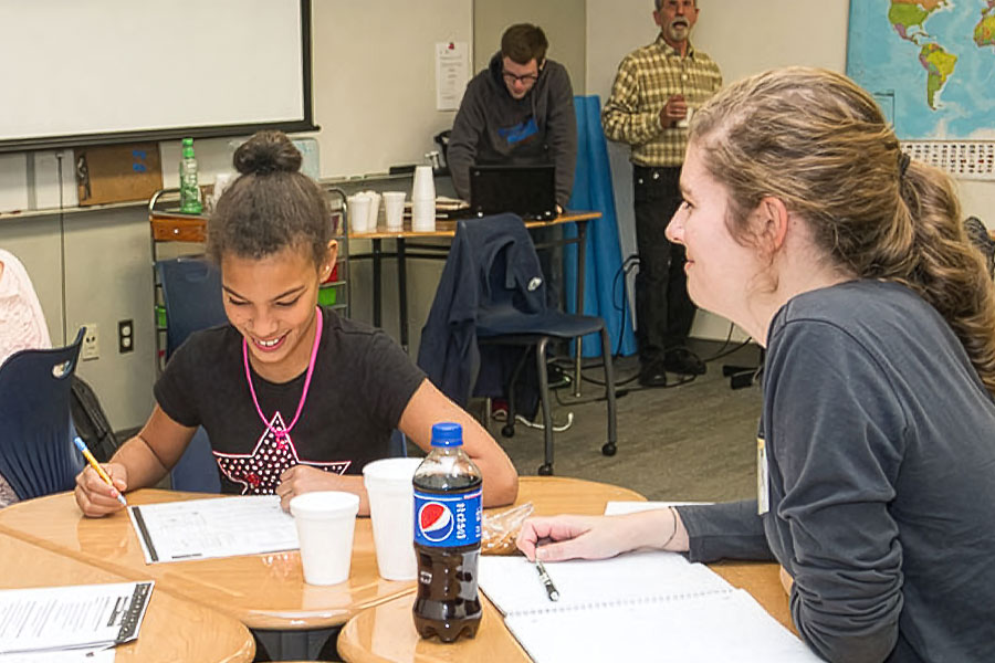 An instructor working one-on-one with a student during a classroom activity.