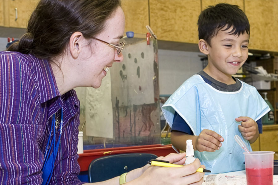 An educator is interacting with a young child during a hands-on activity
