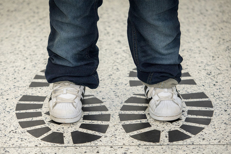 Child standing on large painted footprints on a classroom floor.