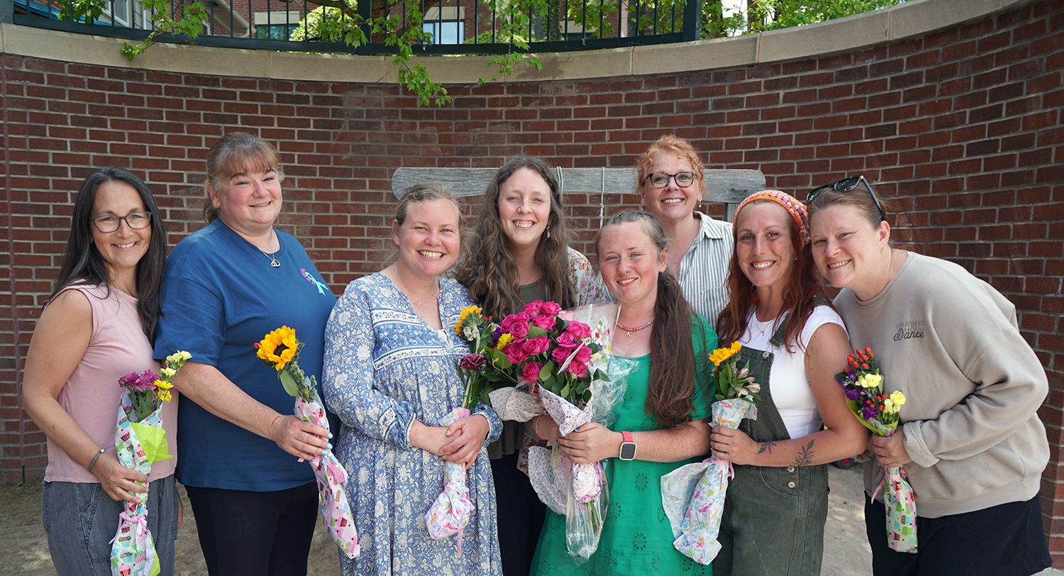 Group of early educators on a playground with flowers. 