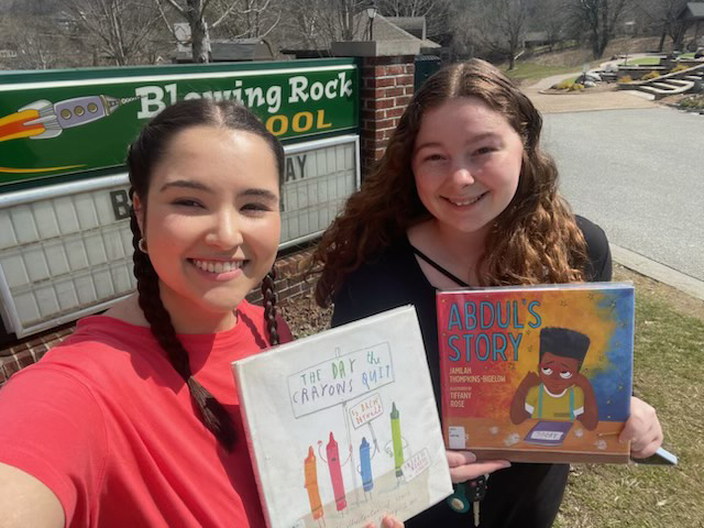 Katelyn Fullbright and Julie Stubbs hold their books in front of the Blowing Rock School sign.