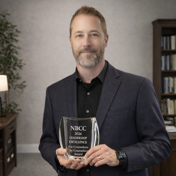 Person in black suit holding glass award.