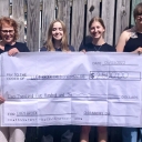 Club officers Kenyon Wills, Caitlyn Moore, and Abby Rowsey present the check to Lucy Brock's director, Dr. Andrea Anderson.