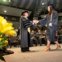 Dean Spooner shakes students hand at commencement.