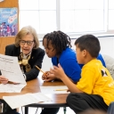 During a recent visit to the Appalachian State University Academy at Middle Fork, Reich College of Education Dean Melba Spooner, left, works with kindergarten and first grade students on a small-group writing assignment. 
