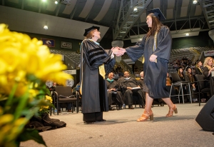 Dean Spooner shakes students hand at commencement.