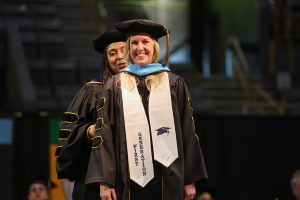 Doctoral student being hooded at commencement.