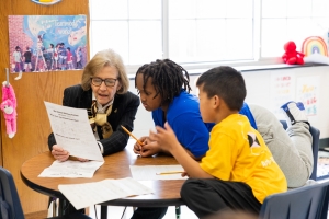During a recent visit to the Appalachian State University Academy at Middle Fork, Reich College of Education Dean Melba Spooner, left, works with kindergarten and first grade students on a small-group writing assignment. 