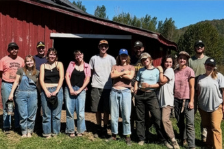 Several volunteers in front of a red barn.