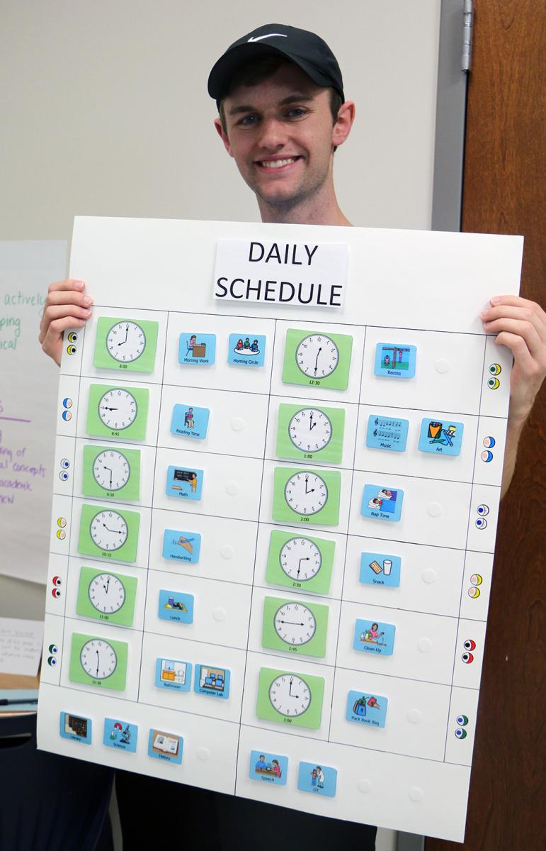 Seth L. holds his Daily Schedule designed to help all students learn to tell time and follow a picture schedule.