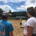 Graduate students Jessica Crandell ’16, left, and Danielle Joyce observe the horses at Lazy Acres Farm during the Equine Assisted Learning and Psychotherapy course. The seeing student practices describing the horses’ actions to the blindfolded student using plain language. Through this trust-building exercise, students learned how to describe behavior without interpretation. Photo by Rebekah Saylors